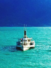 Boat sailing in sea against clear blue sky