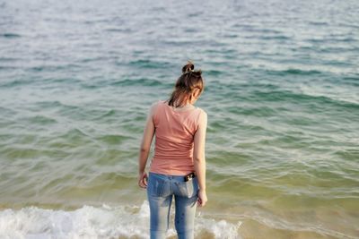 Rear view of woman standing at beach