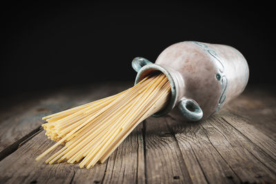 Group of uncooked italian spaghetti pasta inside a terracotta pot on wooden background