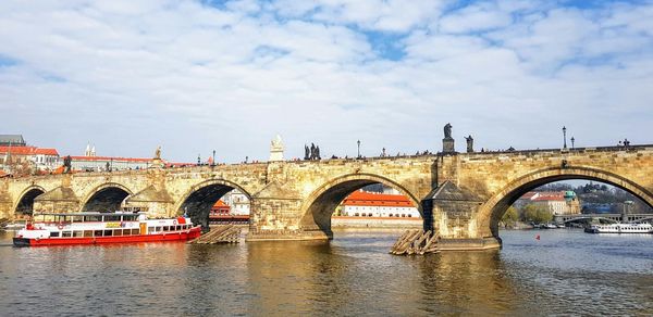 Arch bridge over river against sky in city