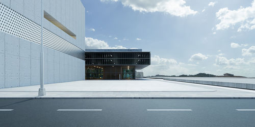 Empty road by building against sky