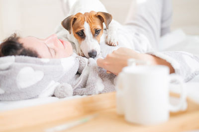 Woman with dog sleeping on bed at home