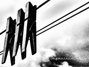 Low angle view of text hanging on fence against sky
