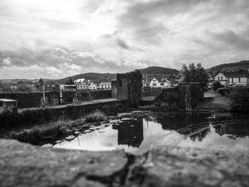 Bridge over river by buildings in city against sky