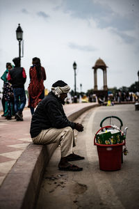 Side view of vendor sitting on footpath in city