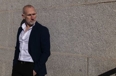 Portrait of adult man in suit standing on street against wall. madrid, spain