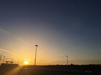 Illuminated street light against clear sky during sunset