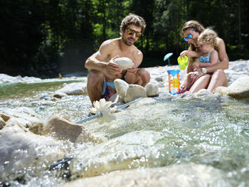 Family with daughter fixing water wheel in a mountain stream