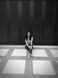 Portrait of woman sitting against wall