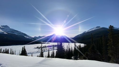 Scenic view of snowcapped mountains against bright sun