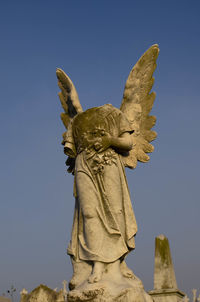 Low angle view of angel statue against blue sky