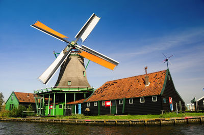 Traditional windmill by building against sky