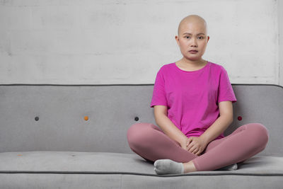 Full length of boy sitting against wall