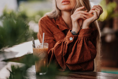 Close-up of female hands and a glass of cold coffee