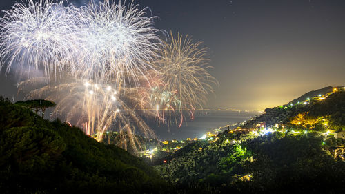 Firework display against sea at night