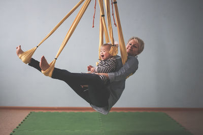 Full length of young woman swinging against wall