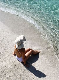 High angle view of woman sitting at shore of beach