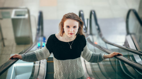 Portrait of smiling young woman standing against wall