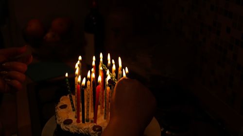 Cropped hand lighting birthday candles at home