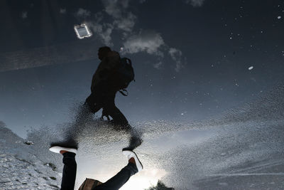 Reflection of man in water against sky