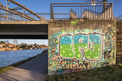 Graffiti on bridge over river against sky