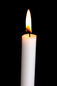 Close-up of burning candle against black background