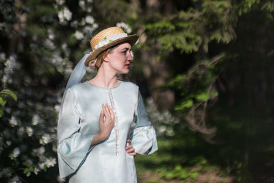 Young woman wearing hat standing against trees