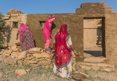 Rear view of woman walking by building against sky