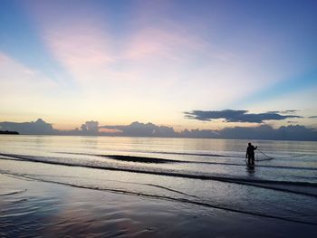 Silhouette man standing by sea against sky during sunset