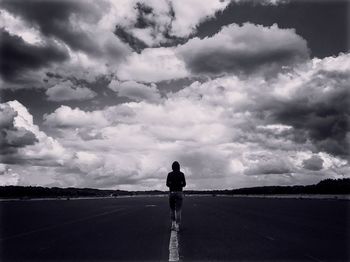 Rear view of woman standing on field against sky