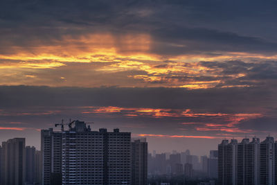 Modern buildings in city against sky during sunset