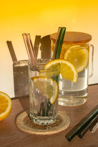 Glass of water with fresh lemon juice with reusable glass straws detox cold tonic water with sunny