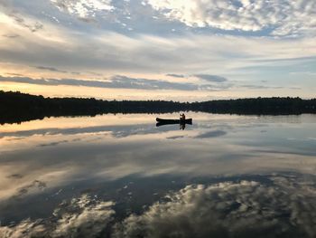 Scenic view of lake with man rowing boat against sky