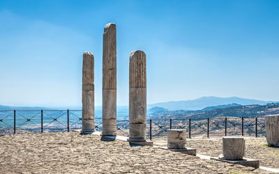 Wooden posts on beach against blue sky