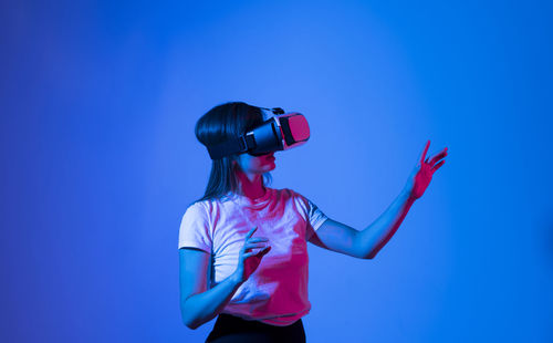 Rear view of woman photographing against blue background