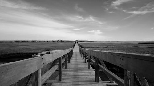 View of wooden footbridge against sky