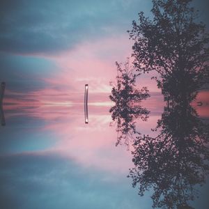 Low angle view of trees against cloudy sky