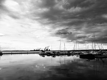 Sailboats moored at harbor against sky