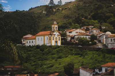 Houses by trees and buildings against sky