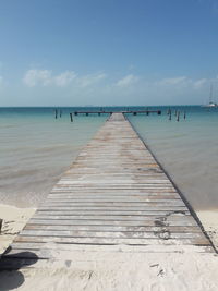 Wooden pier on beach against sky