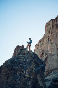 Male climber reading a guide book on the top of the boulder in oregon
