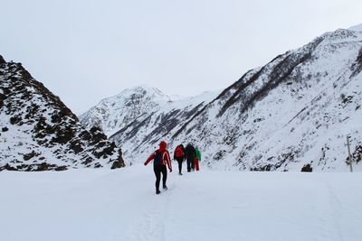 People walking on snow against snowcapped mountains