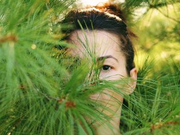 Close-up portrait of woman hiding in tree branches