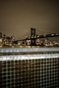 Illuminated bridge over river at night