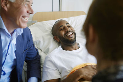 Smiling young patient with eyes closed lying on bed at hospital ward