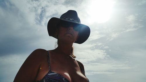 Low angle view of woman wearing hat standing against sky