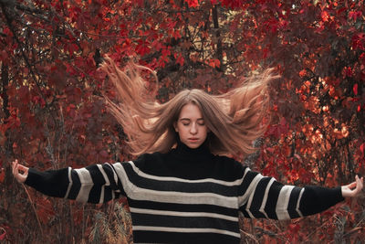 Portrait of smiling young woman standing against trees during autumn