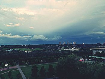 Trees on landscape against cloudy sky