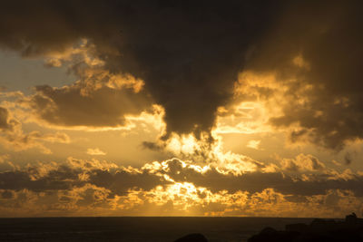 Scenic view of sea against cloudy sky at sunset