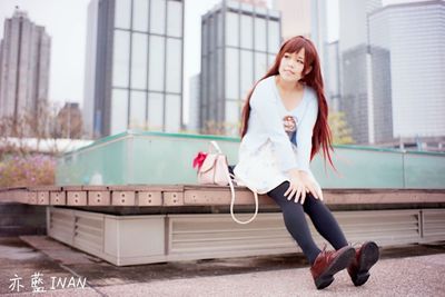 Happy young woman holding umbrella in city